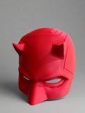 Red mask with horns on a decorative stand against a neutral background