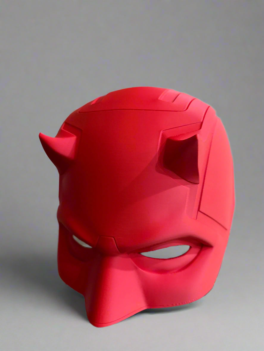 Red mask with horns on a decorative stand against a neutral background
